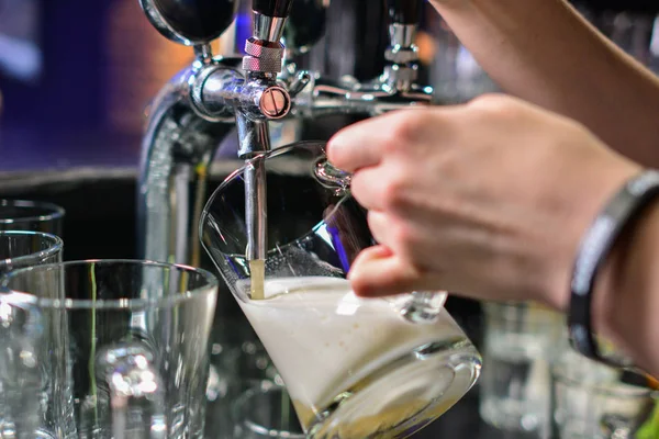 Barmen elini bira fıçısına koyup bira dökerken yakın plan.