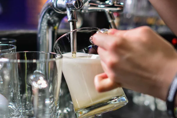 close-up of barman hand at beer tap pouring a draught lager beer