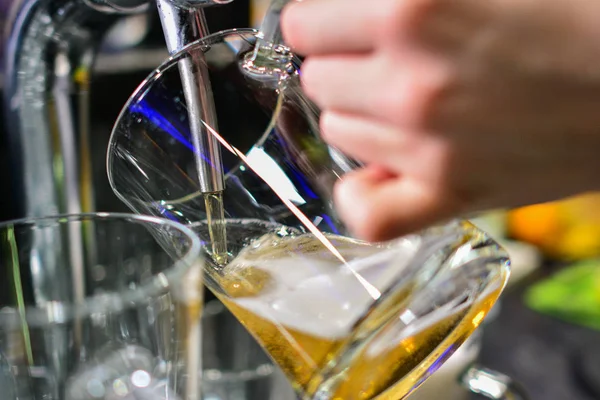 close-up of barman hand at beer tap pouring a draught lager beer