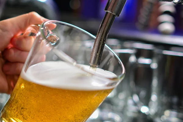 close-up of barman hand at beer tap pouring a draught lager beer