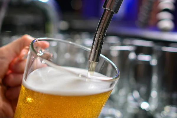 Barmen elini bira fıçısına koyup bira dökerken yakın plan.