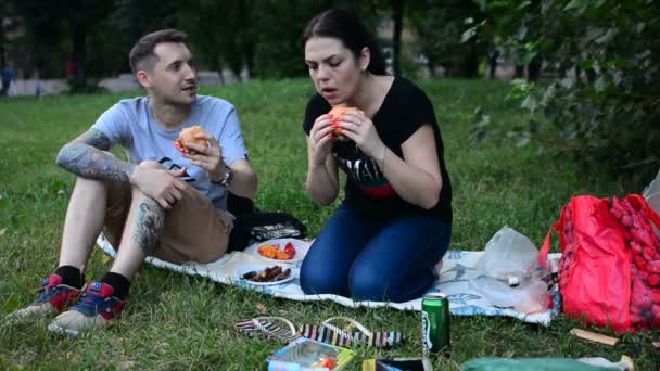 俄罗斯莫斯科 2018年7月21日 阳光明媚的夏季公园的男女 放松一下 吃汉堡和香肠 在草地上的夏季公园里举行交会和野餐 — 图库视频影像