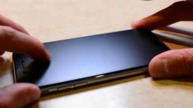 Kırık güvenlik camı mobil telefon yeni adam değişiklikleri. Yeni bir koruyucu cam telefonda yapışır. Yakın çekim yakışıklı.