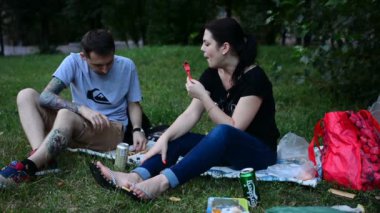 Moskova, Rusya - 21 Temmuz 2018: genç insanlar sandviç yeme ve bira içme piknik bir çim ve konuşuyor, gülüyor. Park yeşil çimenlerin üzerinde oturuyor. Mutlu gençler biraz yiyeceğimiz var..