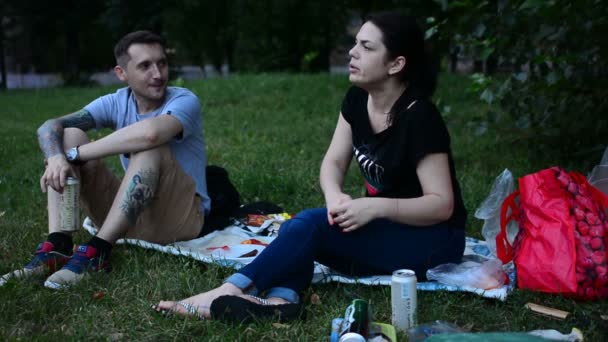 俄罗斯莫斯科 2018年7月21日 年轻人吃三明治和喝啤酒 在草坪野餐 坐在公园的绿草上 快乐的青少年有一些食物 — 图库视频影像