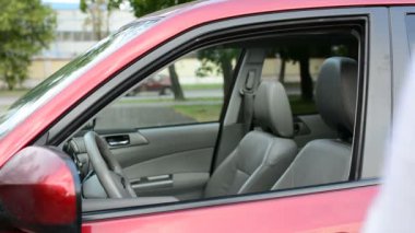 Park boyunca giden adam yerleştirin ve arabasını ve gidiyor oturur. Erkek açık arabanın kapı kaldırmak sinyal