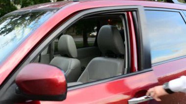 Park boyunca giden adam yerleştirin ve arabasını ve gidiyor oturur. Erkek açık arabanın kapı kaldırmak sinyal