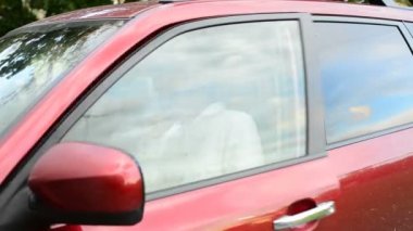 Park boyunca giden adam yerleştirin ve arabasını ve gidiyor oturur. Erkek açık arabanın kapı kaldırmak sinyal