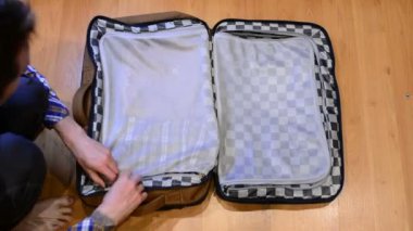 Üstten görünüm seyahat kavramı adam sıralama ve elbiselerini bavul paketleme