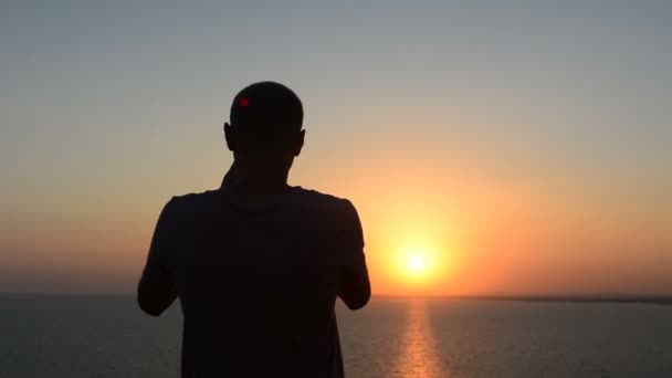 Groupe de jeunes amis adultes profitant d'un coucher de soleil à la mer assis sur des rochers — Video