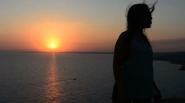 Açık havada bir günbatımı güneş parlak arkasında bir ufukta parlayan ile dans aktif genç kadın siluet.