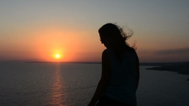 Actieve jonge vrouw silhouet dansen buitenshuis op een zonsondergang met de zon schijnt fel achter haar aan een horizon. — Stockvideo