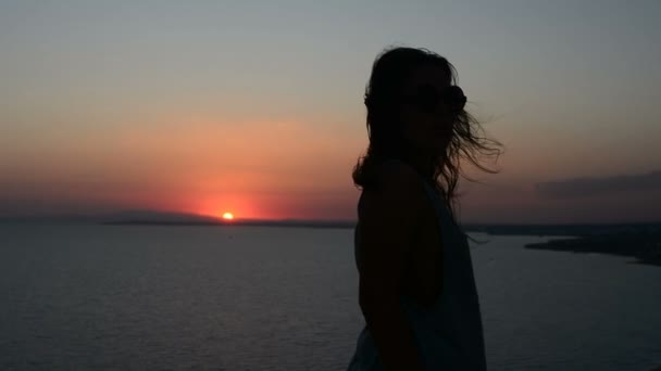 Silueta de una mujer que se mueve sobre un fondo al atardecer, una dama baila sobre la arena por la noche, su pelo ondeando al viento — Vídeo de stock