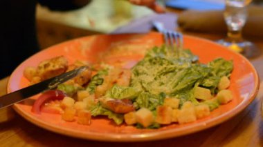 Sezar salata kırmızı maşa, parmesan peyniri, sos, plaka üzerinde makro closeup maşa, hareketli, arka planda yeme insanlar