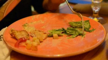 Sezar salata kırmızı maşa, parmesan peyniri, sos, plaka üzerinde makro closeup maşa, hareketli, arka planda yeme insanlar