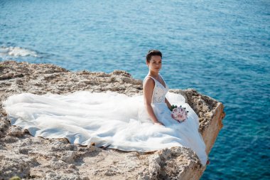 Genç gelin ve damat sahilde yürüyüş, Öpüşme ve sahip eğlenceli, düğün töreni kayalar ve deniz yakınında gülümseyen güzel. Kıbrıs Sahil düğün töreni