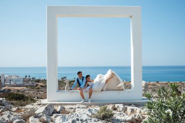 Genç gelin ve damat sahilde yürüyüş, Öpüşme ve sahip eğlenceli, düğün töreni kayalar ve deniz yakınında gülümseyen güzel. Kıbrıs Sahil düğün töreni