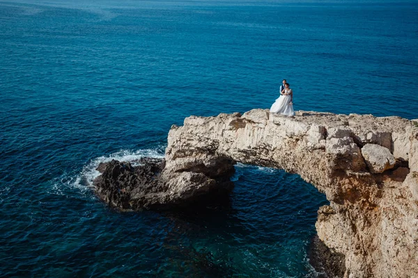 Genç gelin ve damat sahilde yürüyüş, Öpüşme ve sahip eğlenceli, düğün töreni kayalar ve deniz yakınında gülümseyen güzel. Kıbrıs Sahil düğün töreni