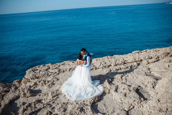 Genç gelin ve damat sahilde yürüyüş, Öpüşme ve sahip eğlenceli, düğün töreni kayalar ve deniz yakınında gülümseyen güzel. Kıbrıs Sahil düğün töreni