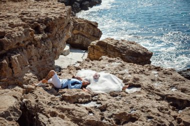 Genç gelin ve damat sahilde yürüyüş, Öpüşme ve sahip eğlenceli, düğün töreni kayalar ve deniz yakınında gülümseyen güzel. Kıbrıs Sahil düğün töreni