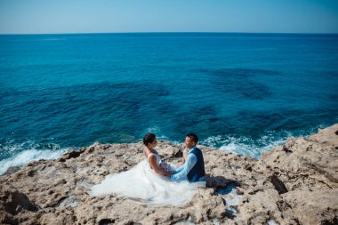 Genç gelin ve damat sahilde yürüyüş, Öpüşme ve sahip eğlenceli, düğün töreni kayalar ve deniz yakınında gülümseyen güzel. Kıbrıs Sahil düğün töreni
