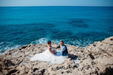 Genç gelin ve damat sahilde yürüyüş, Öpüşme ve sahip eğlenceli, düğün töreni kayalar ve deniz yakınında gülümseyen güzel. Kıbrıs Sahil düğün töreni