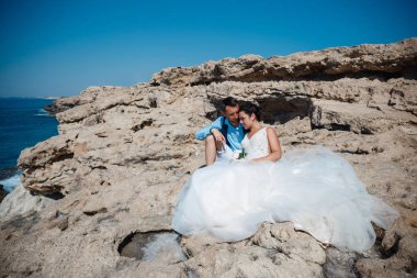 Genç gelin ve damat sahilde yürüyüş, Öpüşme ve sahip eğlenceli, düğün töreni kayalar ve deniz yakınında gülümseyen güzel. Kıbrıs Sahil düğün töreni