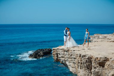 Genç gelin ve damat sahilde yürüyüş, Öpüşme ve sahip eğlenceli, düğün töreni kayalar ve deniz yakınında gülümseyen güzel. Kıbrıs Sahil düğün töreni