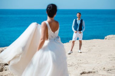 Genç gelin ve damat sahilde yürüyüş, Öpüşme ve sahip eğlenceli, düğün töreni kayalar ve deniz yakınında gülümseyen güzel. Kıbrıs Sahil düğün töreni