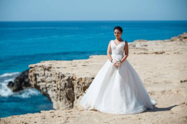 Genç gelin ve damat sahilde yürüyüş, Öpüşme ve sahip eğlenceli, düğün töreni kayalar ve deniz yakınında gülümseyen güzel. Kıbrıs Sahil düğün töreni