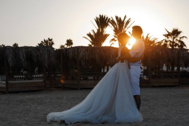 Genç gelin ve damat sahilde yürüyüş, Öpüşme ve sahip eğlenceli, düğün töreni kayalar ve deniz yakınında gülümseyen güzel. Kıbrıs Sahil düğün töreni