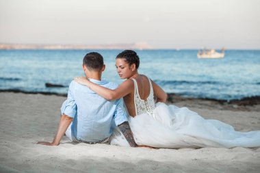 Genç gelin ve damat sahilde yürüyüş, Öpüşme ve sahip eğlenceli, düğün töreni kayalar ve deniz yakınında gülümseyen güzel. Kıbrıs Sahil düğün töreni