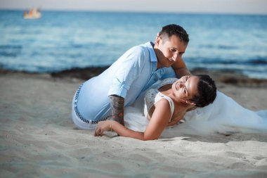 Genç gelin ve damat sahilde yürüyüş, Öpüşme ve sahip eğlenceli, düğün töreni kayalar ve deniz yakınında gülümseyen güzel. Kıbrıs Sahil düğün töreni