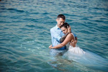Genç gelin ve damat sahilde yürüyüş, Öpüşme ve sahip eğlenceli, düğün töreni kayalar ve deniz yakınında gülümseyen güzel. Kıbrıs Sahil düğün töreni