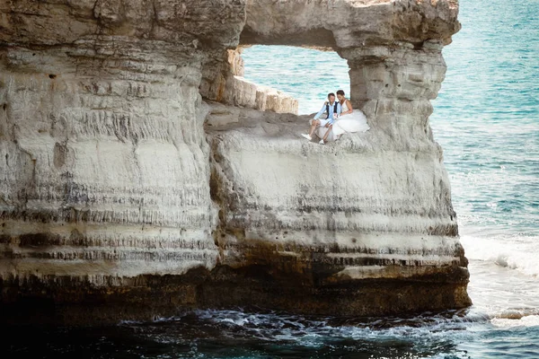 Genç gelin ve damat sahilde yürüyüş, Öpüşme ve sahip eğlenceli, düğün töreni kayalar ve deniz yakınında gülümseyen güzel. Kıbrıs Sahil düğün töreni