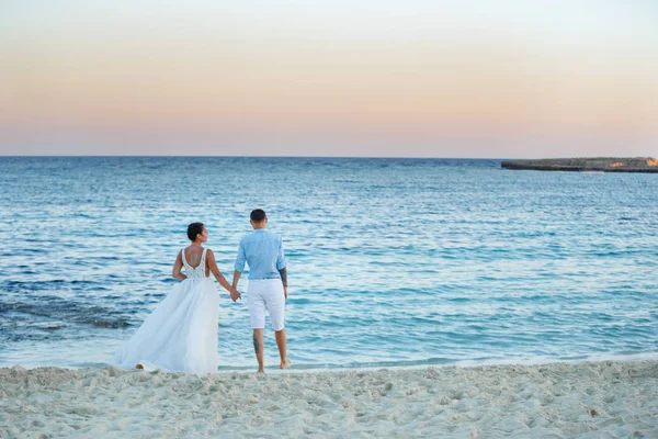 Genç gelin ve damat sahilde yürüyüş, Öpüşme ve sahip eğlenceli, düğün töreni kayalar ve deniz yakınında gülümseyen güzel. Kıbrıs Sahil düğün töreni