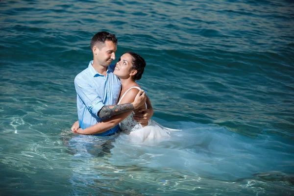 Genç gelin ve damat sahilde yürüyüş, Öpüşme ve sahip eğlenceli, düğün töreni kayalar ve deniz yakınında gülümseyen güzel. Kıbrıs Sahil düğün töreni