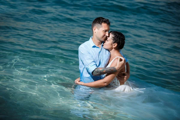 Genç gelin ve damat sahilde yürüyüş, Öpüşme ve sahip eğlenceli, düğün töreni kayalar ve deniz yakınında gülümseyen güzel. Kıbrıs Sahil düğün töreni