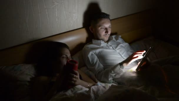 Young Couple Smartphone Tablet Lying Bed Late Night Home — Stock Video