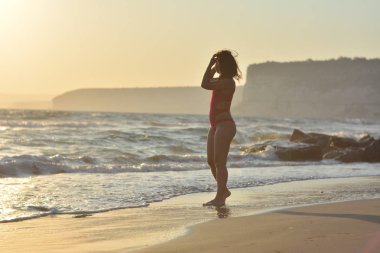Kırmızı bir mayo içinde sahilde poz güzel mutlu esmer kız.