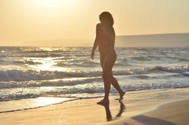 Kırmızı bir mayo içinde sahilde poz güzel mutlu esmer kız.