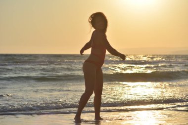 Kırmızı bir mayo içinde sahilde poz güzel mutlu esmer kız.