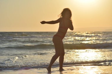 Kırmızı bir mayo içinde sahilde poz güzel mutlu esmer kız.