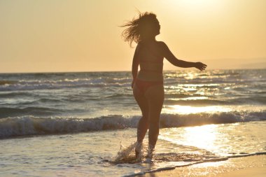 Kırmızı bir mayo içinde sahilde poz güzel mutlu esmer kız.