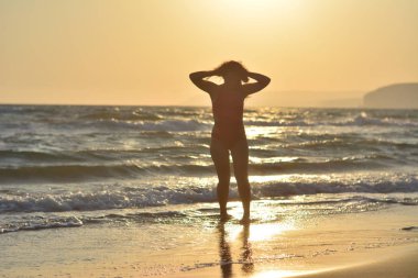 Kırmızı bir mayo içinde sahilde poz güzel mutlu esmer kız.