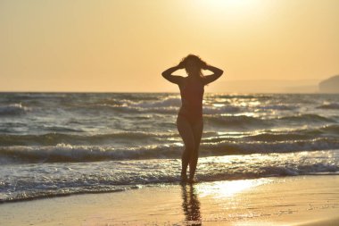 Kırmızı bir mayo içinde sahilde poz güzel mutlu esmer kız.