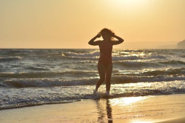 Kırmızı bir mayo içinde sahilde poz güzel mutlu esmer kız.