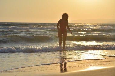 Kırmızı bir mayo içinde sahilde poz güzel mutlu esmer kız.