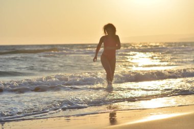 Kırmızı bir mayo içinde sahilde poz güzel mutlu esmer kız.
