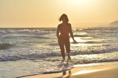 Kırmızı bir mayo içinde sahilde poz güzel mutlu esmer kız.